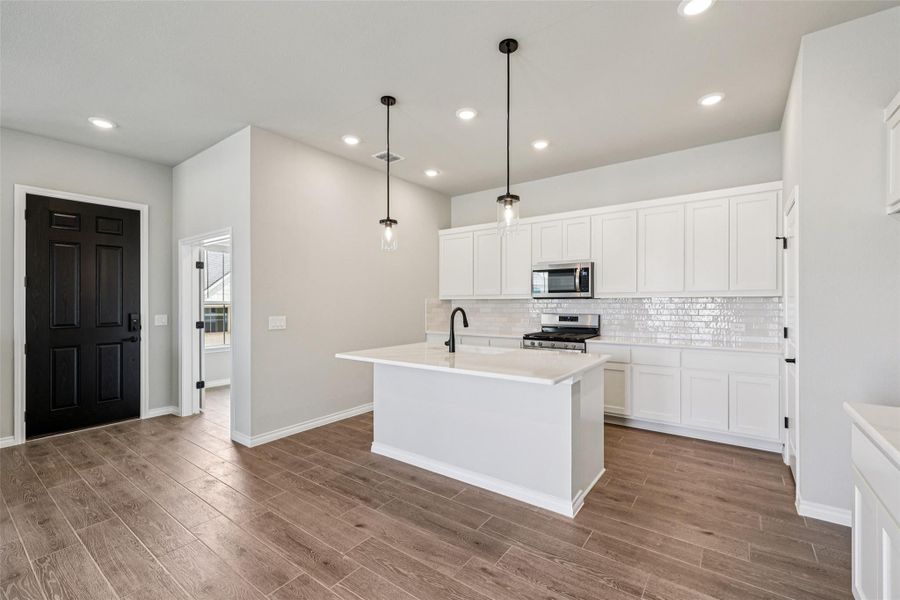 Kitchen featuring appliances with stainless steel finishes, backsplash, wood finished floors, white cabinets, and recessed lighting Kitchen featuring appliances with stainless steel finishes, backsplash, wood finished floors, white cabinets, and recessed lighting