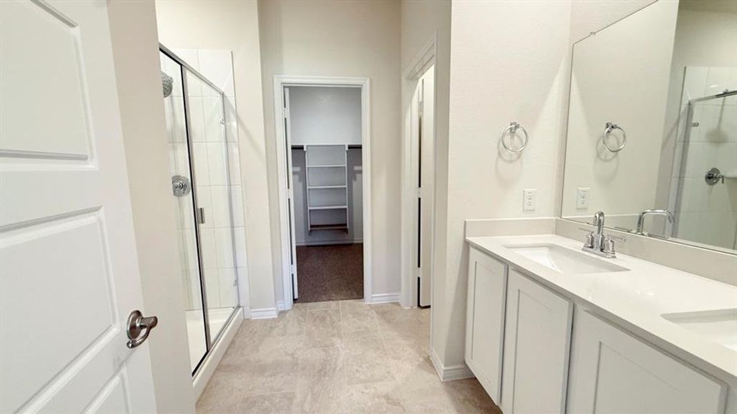Full bathroom with a shower stall, double vanity, and a walk in closet Full bathroom with a shower stall, double vanity, and a walk in closet