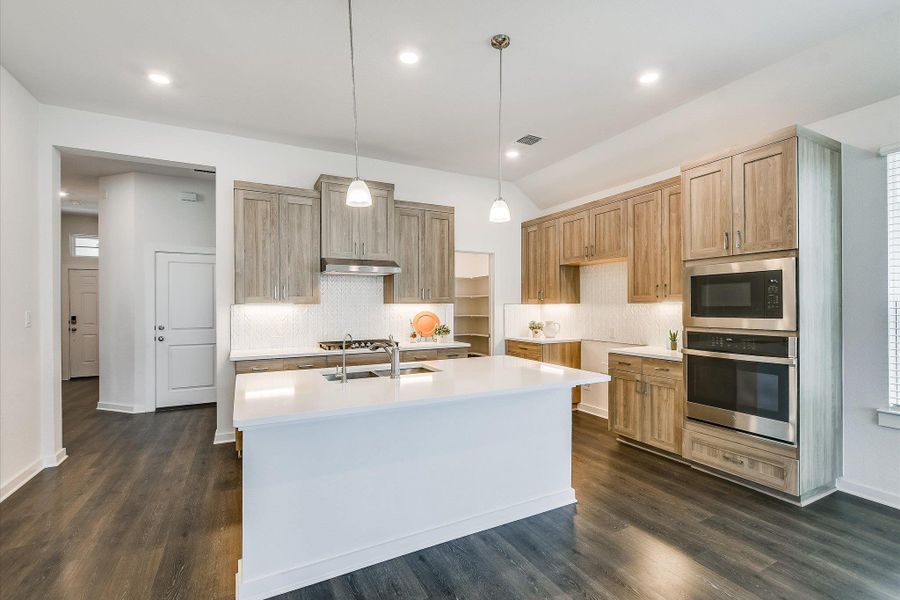Kitchen featuring a central island with an integrated sink, pendant lighting, and  soft-close cabinetry.