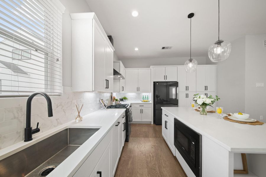 The stainless steel under-mount sink features a black faucet and as an added bonus, the refrigerator will remain with the home, offering added value and convenience. The stainless steel under-mount sink features a black faucet and as an added bonus, the refrigerator will remain with the home, offering added value and convenience.
