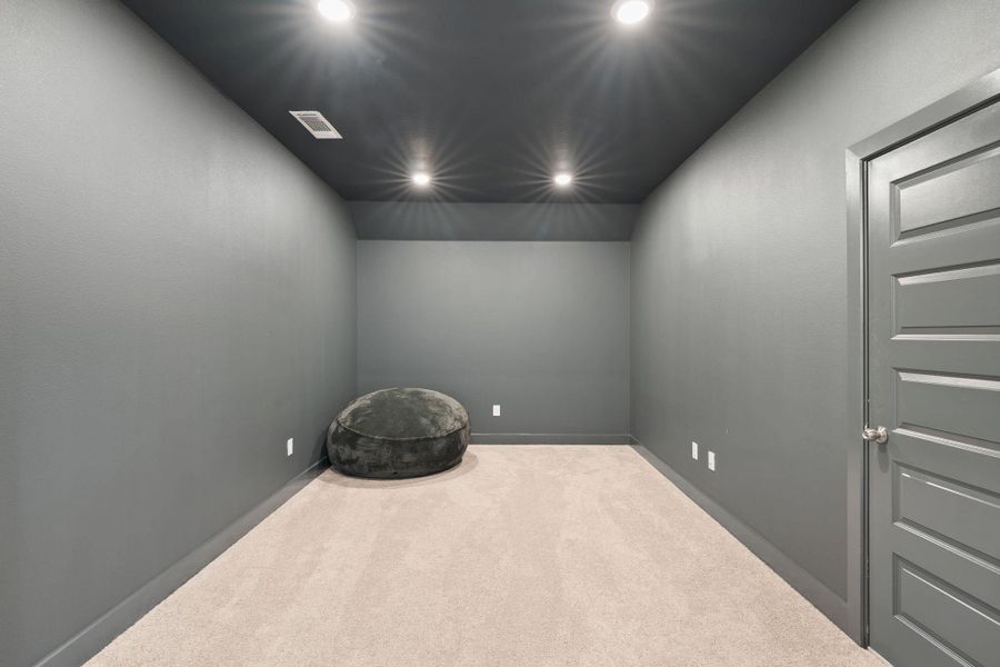 Recessed lighting illuminates this versatile bonus room, perfect for a dedicated media space or quiet retreat.