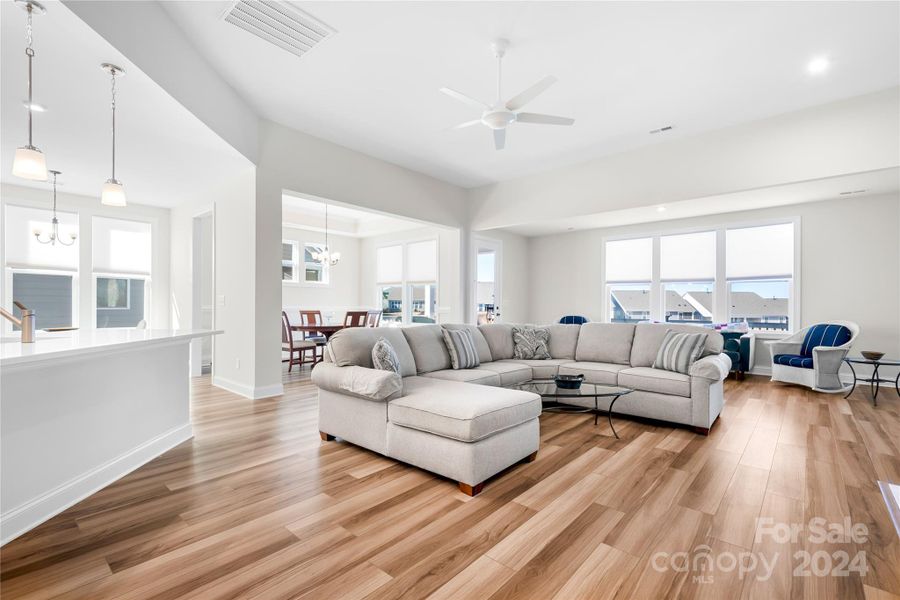 Stunning Great Room and extended Sunroom with LVP flooring, ceiling fan, custom window treatments and natural GAS vented fireplace flow together seamlessly for effortless entertaining.