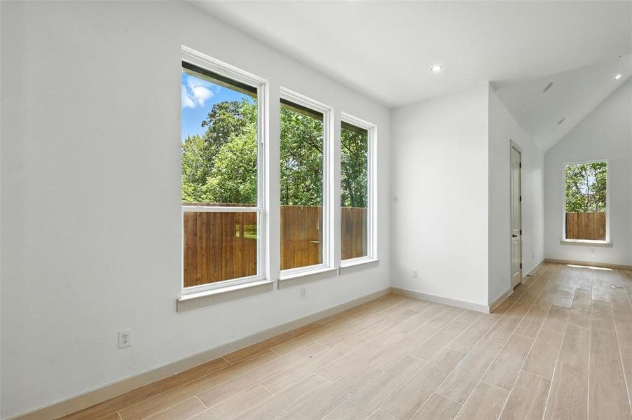 Unfurnished room featuring plenty of natural light, lofted ceiling, wood finish floors, and recessed lighting Unfurnished room featuring plenty of natural light, lofted ceiling, wood finish floors, and recessed lighting