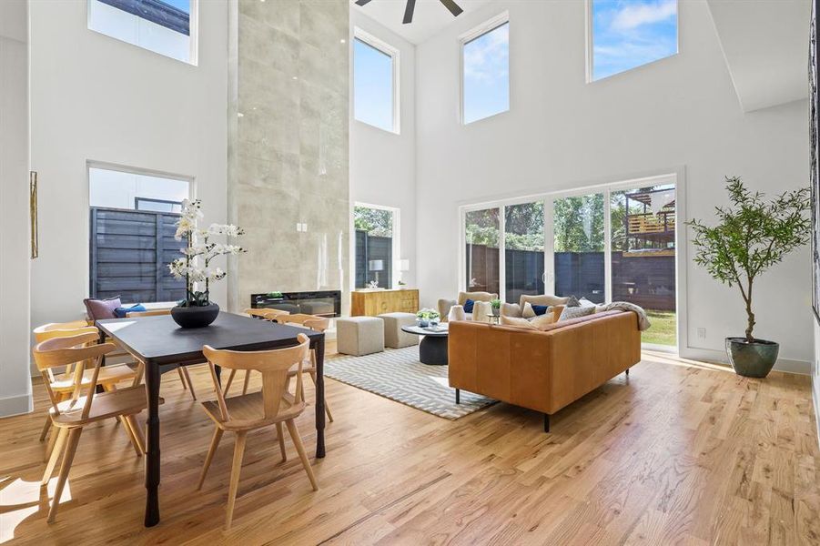 Living room featuring ceiling fan, a high ceiling, and light hardwood / wood-style flooring