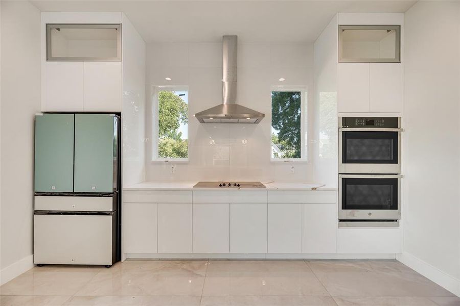 Kitchen featuring white cabinetry, freestanding refrigerator, modern cabinets, exhaust hood, and stainless steel double oven Kitchen featuring white cabinetry, freestanding refrigerator, modern cabinets, exhaust hood, and stainless steel double oven