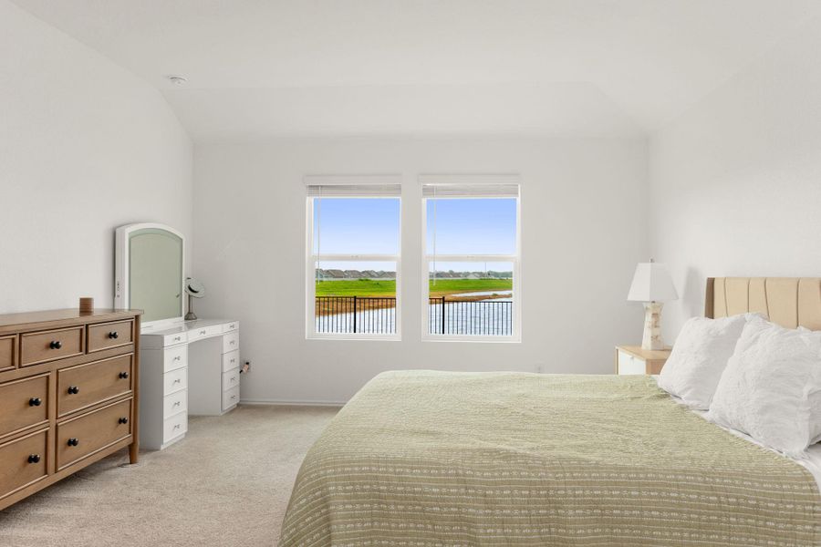Overlook verdant landscapes and a tranquil pond from this naturally illuminated, airy bedroom with a high ceiling.