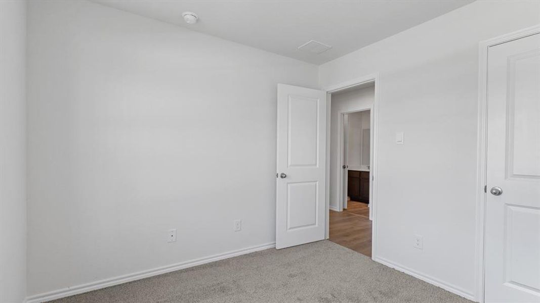Neutral tone interior featuring a light gray carpet, white baseboards, and white walls