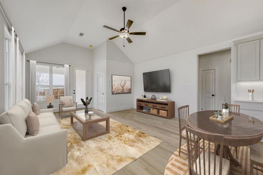 Virtually staged photo - Living area with light wood-style floors, a ceiling fan, and a high ceiling