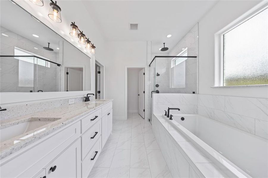Full bathroom with double vanity, a shower stall, a bath, and light marble finish floors