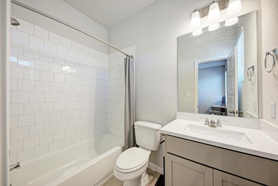 Bathroom featuring a textured wall, shower / bath combo, and vanity