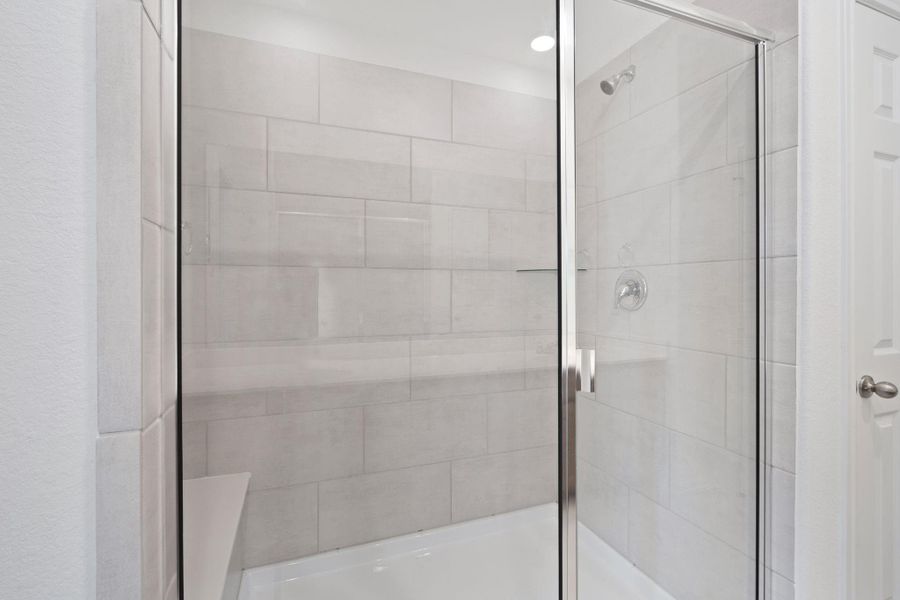 This additional view of your primary bathroom features tile flooring, fresh paint, walk-in shower, a separate garden tub, and a large walk-in closet.