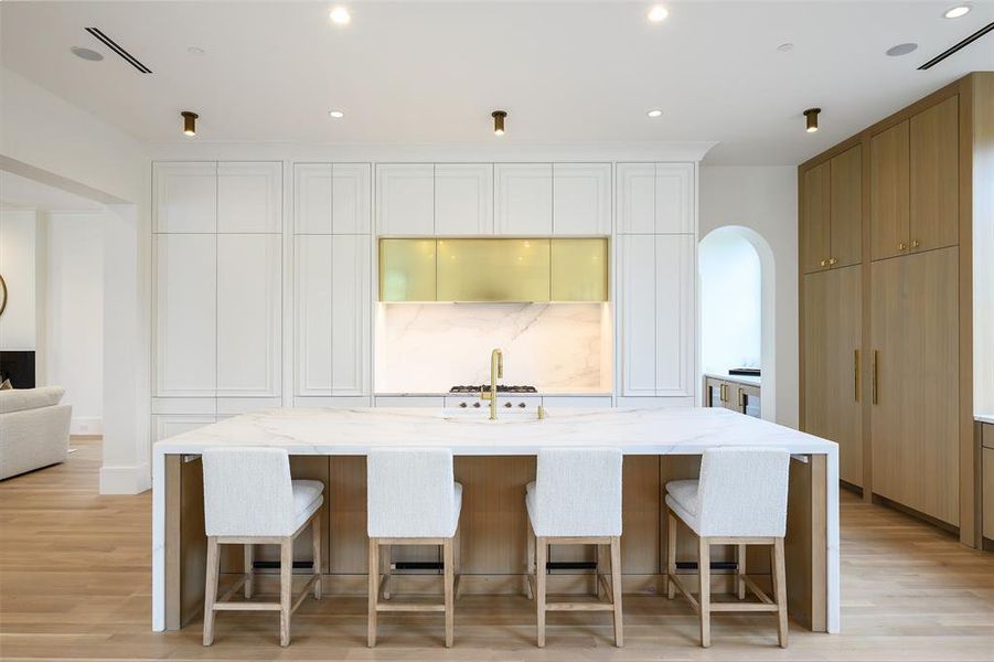 Kitchen with light stone counters, a breakfast bar, recessed lighting, and light wood finished floors Kitchen with light stone counters, a breakfast bar, recessed lighting, and light wood finished floors