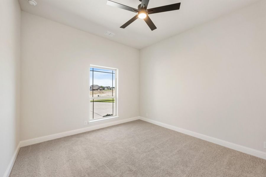 Empty bedroom with carpet flooring, ceiling fan, and single window overlooking neighborhood