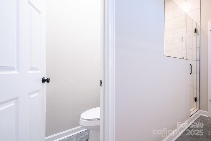 Spacious primary bath with double quartz vanity, custom cabinetry, and an illuminated mirror for a modern finish.