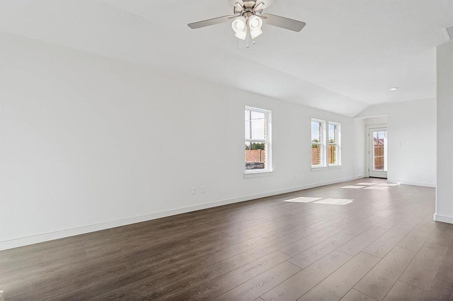 Empty room with lofted ceiling, ceiling fan, and dark hardwood / wood-style floors