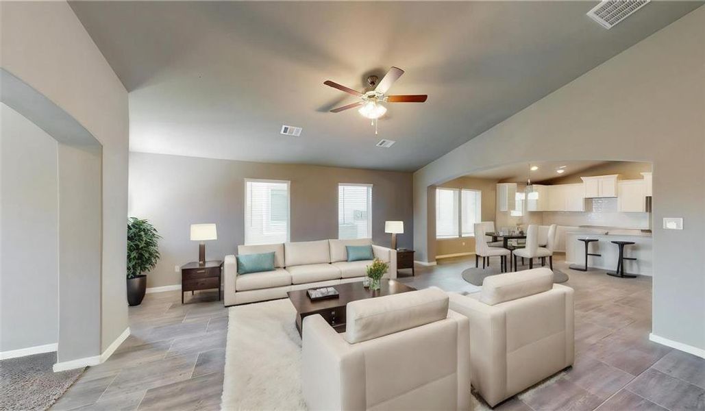 This spacious living area features abundant natural light, modern tile flooring, and an open layout that seamlessly connects to the kitchen and dining spaces. Perfect for both relaxing and entertaining, the area is enhanced by a stylish ceiling fan and neutral color palette. This is a picture of an Elise Floor Plan with another Saratoga Homes.