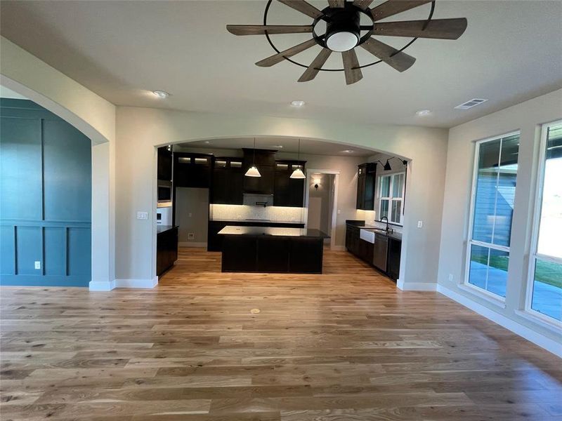 Expansive open-concept living space featuring wood-finish flooring, a decorative ceiling fan, and recessed lighting