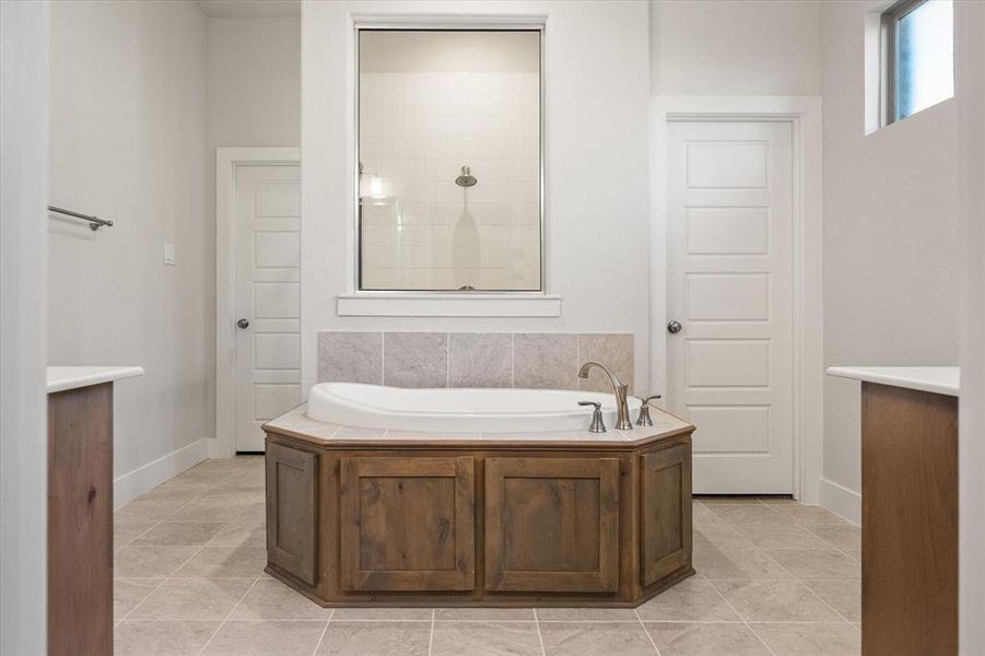 Bathroom with a garden tub, separate shower, private water closet, walk-in closet and tile floors.