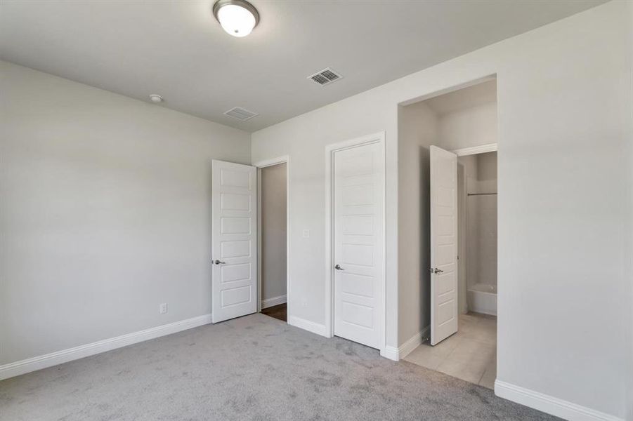 Unfurnished bedroom featuring light carpet and ensuite bath