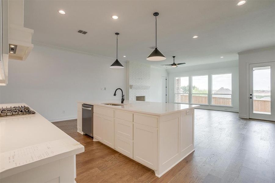 Kitchen with white cabinets, an island with sink, sink, light hardwood / wood-style flooring, and appliances with stainless steel finishes