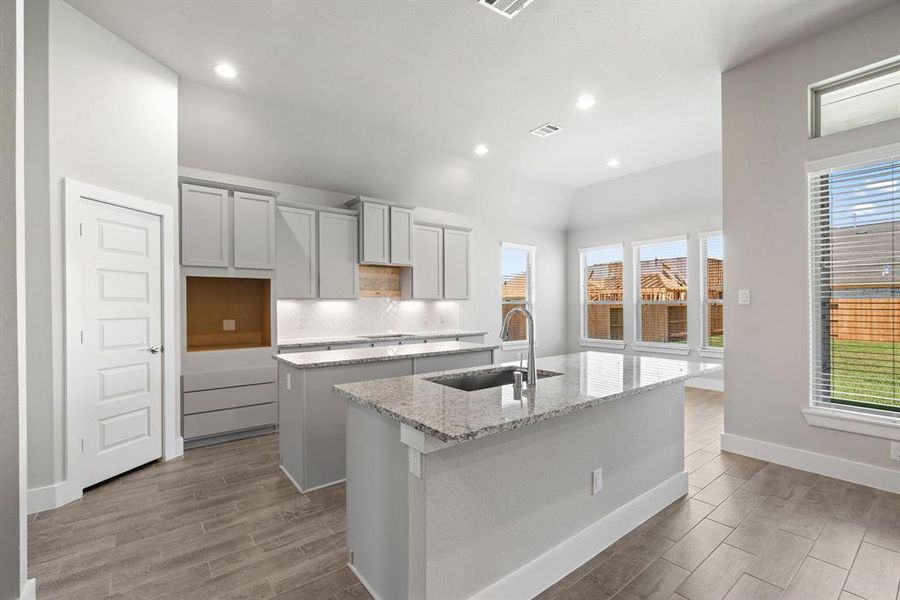 Discover another perspective of this stunning kitchen, generously appointed with an abundance of counter space. Sample photo of completed home with similar floor plan. As-built interior colors and selections may vary.