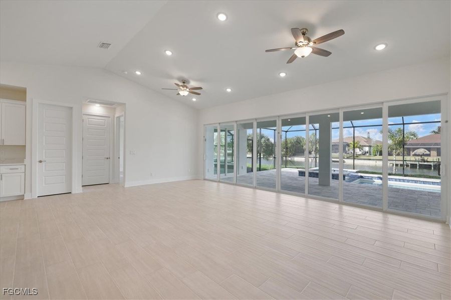 Living room featuring 24 foot slider, recessed lighting, lofted ceiling, ceiling fan, and wood tiled floors