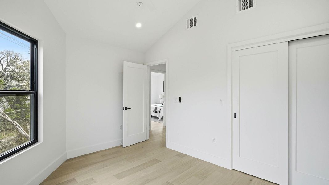 Unfurnished bedroom featuring light wood-type flooring, lofted ceiling, recessed lighting, and a closet