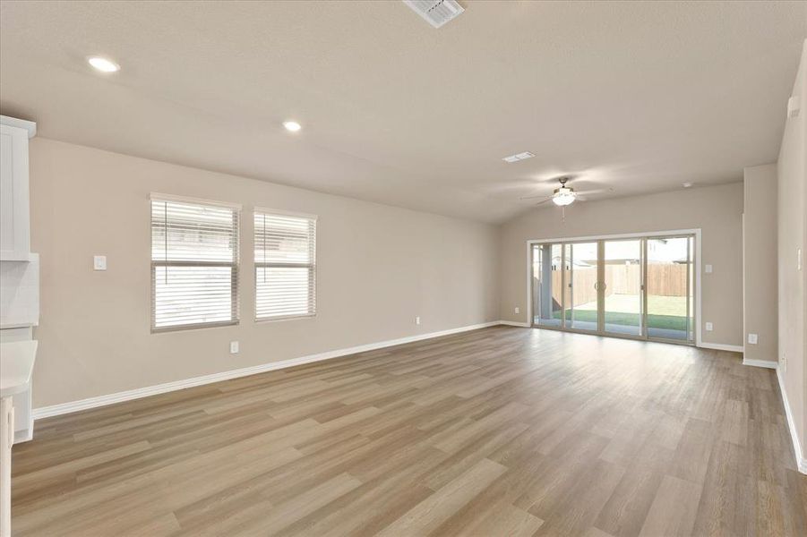 Unfurnished living room with light wood-type flooring, recessed lighting, lofted ceiling, and ceiling fan Unfurnished living room with light wood-type flooring, recessed lighting, lofted ceiling, and ceiling fan