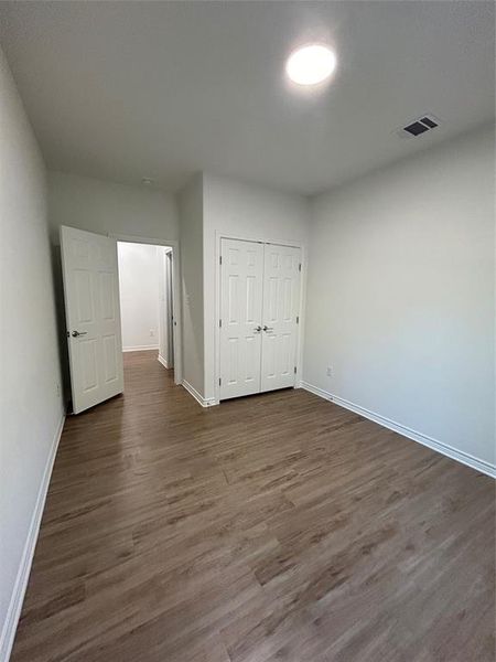 Bedroom with dark wood-type flooring and a closet