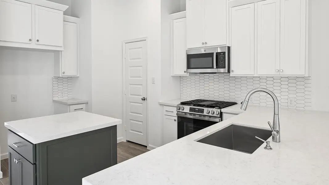 Kitchen with backsplash, stainless steel appliances, light stone counters, and white cabinets Kitchen with backsplash, stainless steel appliances, light stone counters, and white cabinets