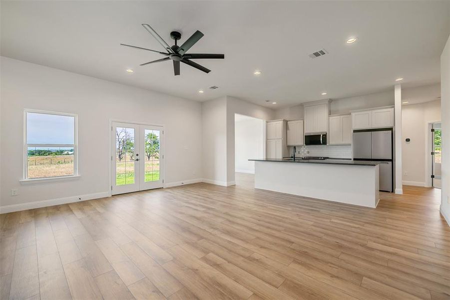 Unfurnished living room with a ceiling fan, recessed lighting, healthy amount of natural light, and light wood-style flooring