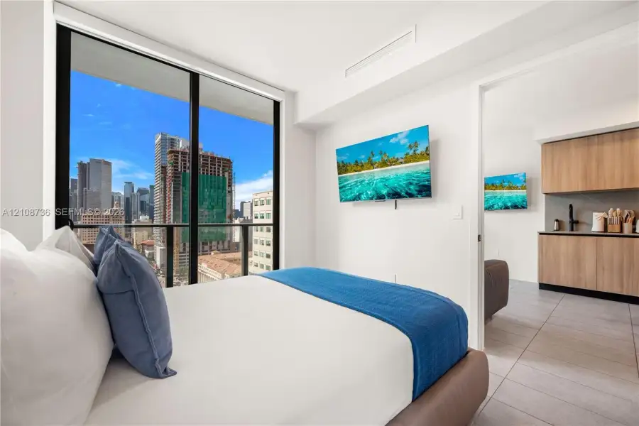 Floor-to-ceiling windows, city skyline backdrop, wood-finish cabinetry, tile flooring, and neutral wall finishes Floor-to-ceiling windows, city skyline backdrop, wood-finish cabinetry, tile flooring, and neutral wall finishes