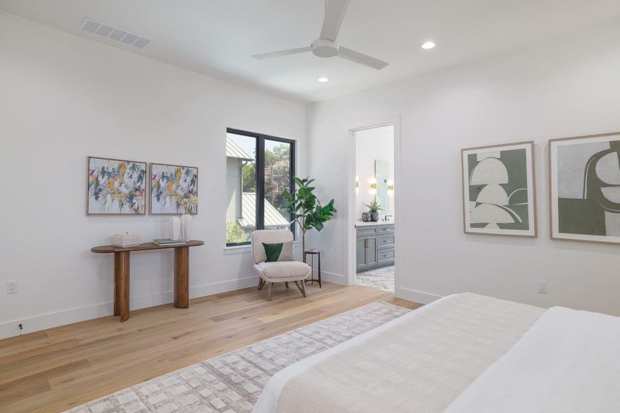 Spacious room featuring wood-finish flooring, white walls, and a ceiling fan
