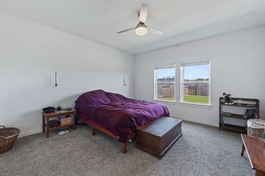 Retreat to this primary bedroom with views of the large backyard!