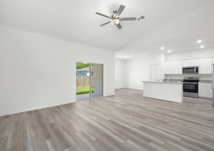 Family room of the Braden - FL home in Fort Pierce, featuring a sliding glass door to the covered patio and an open kitchen.
