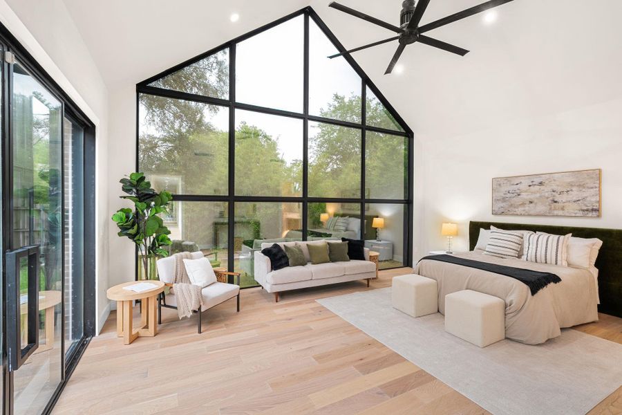 Vaulted ceiling bedroom featuring expansive floor-to-ceiling windows with black frames, wood-finish flooring, and recessed lighting