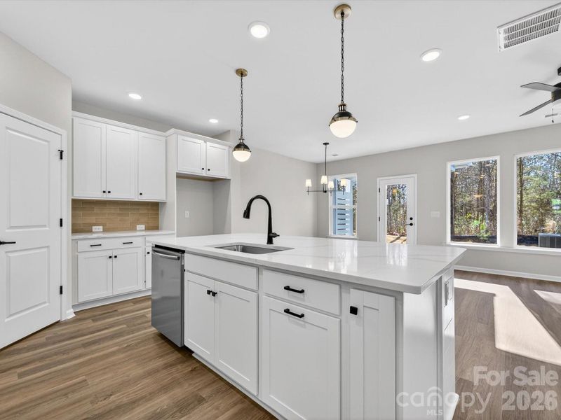 Open kitchen features 42" cabinets with soft close doors & drawers with large kitchen shiplap Island, quartz countertops, single bowl SS sink, tiled backsplash, Frigidaire gallery range appliances which are vented to outside of the home. Large walk-in pantry with solid shelving.