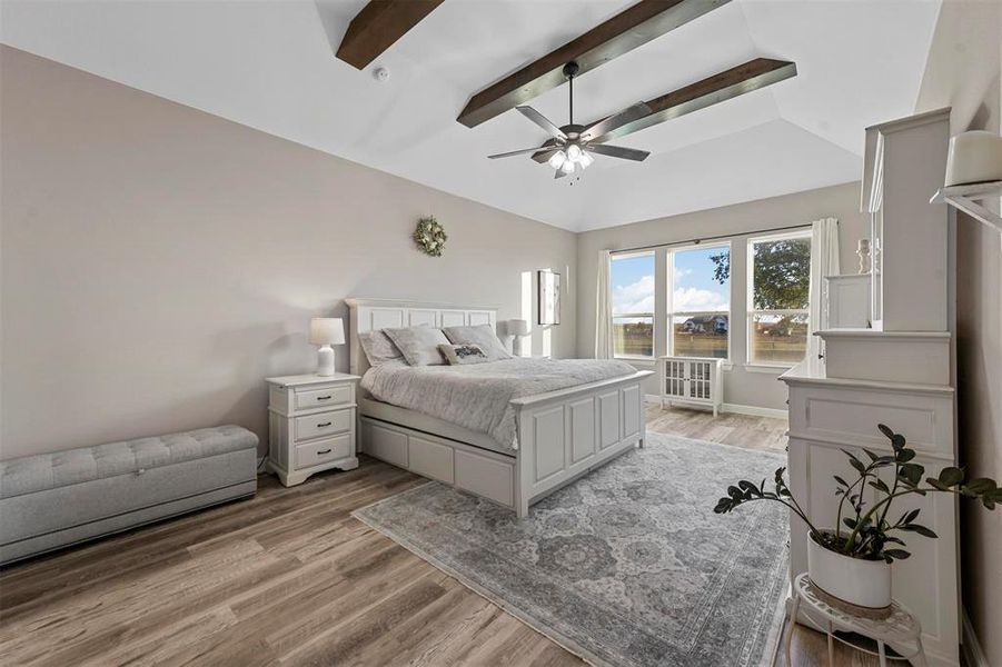 Bedroom featuring vaulted ceiling with beams, light hardwood / wood-style floors, and ceiling fan