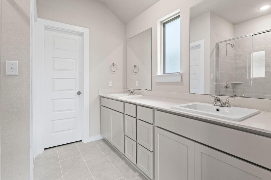 Two individual sinks grace the broad vanity, illuminated by natural light from the frosted window.