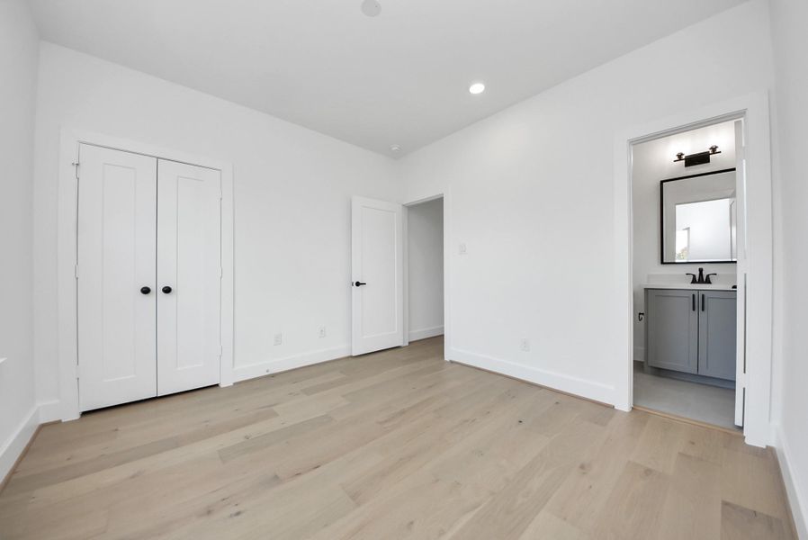Step into this bright, modern bedroom, featuring ample natural light and a clean, neutral palette. The double-door closet and en-suite bathroom with a sleek vanity and mirror make it a personal retreat ready for your style.