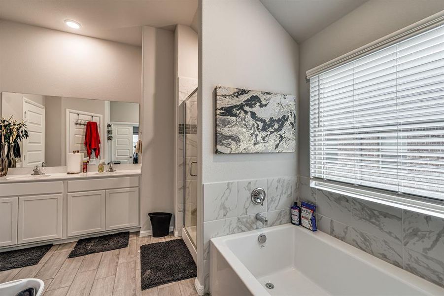 Bathroom with vanity, separate shower and tub, and wood-type flooring