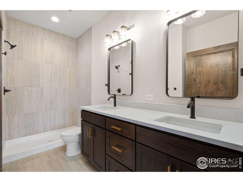 Main floor primary bathroom with quartz countertops and walk in closet