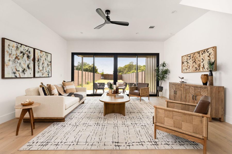 Natural light floods this living space, highlighting sleek wood flooring and a modern ceiling fan.