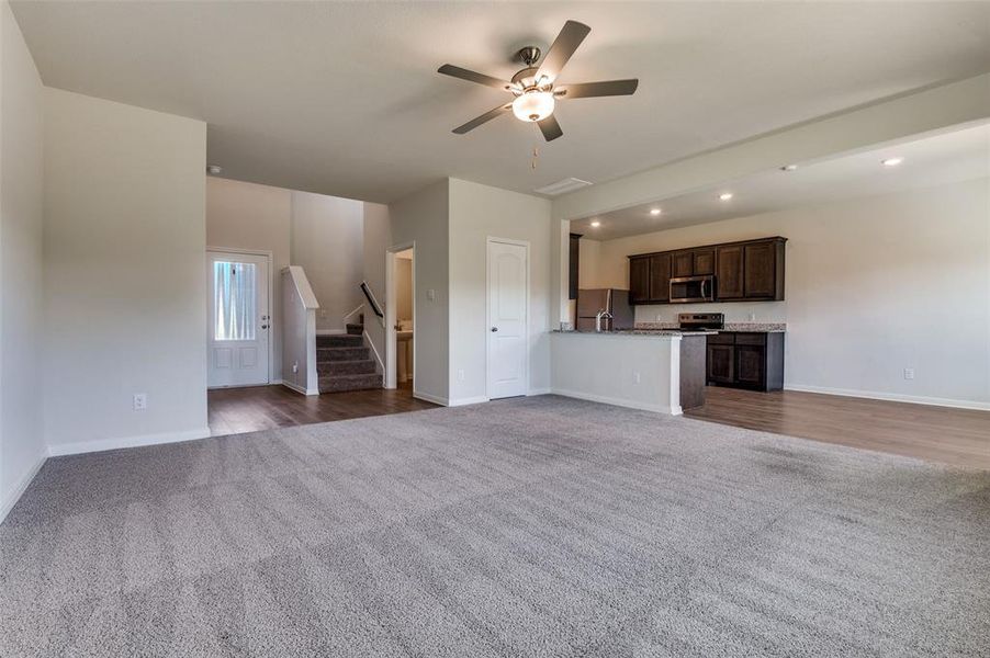 Unfurnished living room featuring dark colored carpet, ceiling fan, and recessed lighting