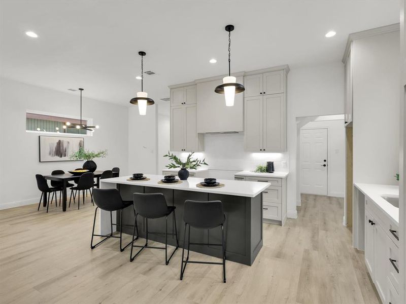 Kitchen with a breakfast bar, light hardwood / wood-style flooring, a chandelier, a center island, and hanging light fixtures