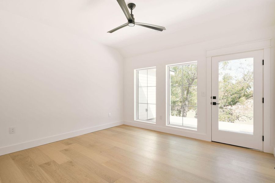 Empty room with light wood-style flooring, lofted ceiling, and ceiling fan Empty room with light wood-style flooring, lofted ceiling, and ceiling fan