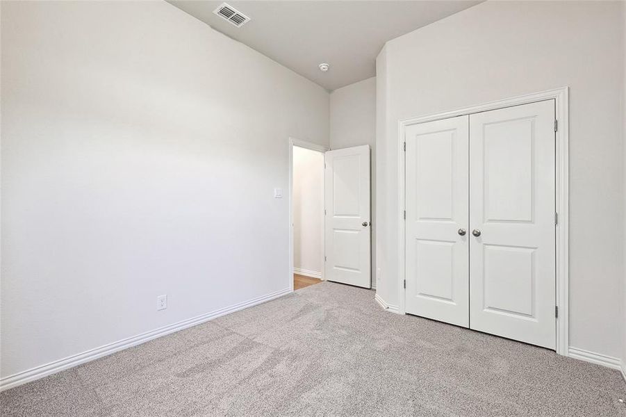 Unfurnished bedroom featuring a closet and light colored carpet