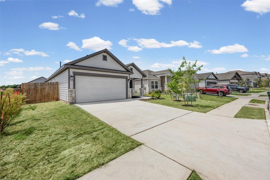 A wide concrete driveway leads to the attached front-loading garage of this single-family home. A wide concrete driveway leads to the attached front-loading garage of this single-family home.