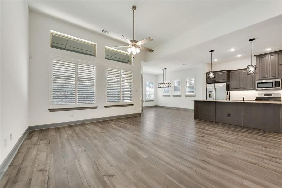 Kitchen with light hardwood / wood-style floors, dark brown cabinets, ceiling fan, and stainless steel appliances