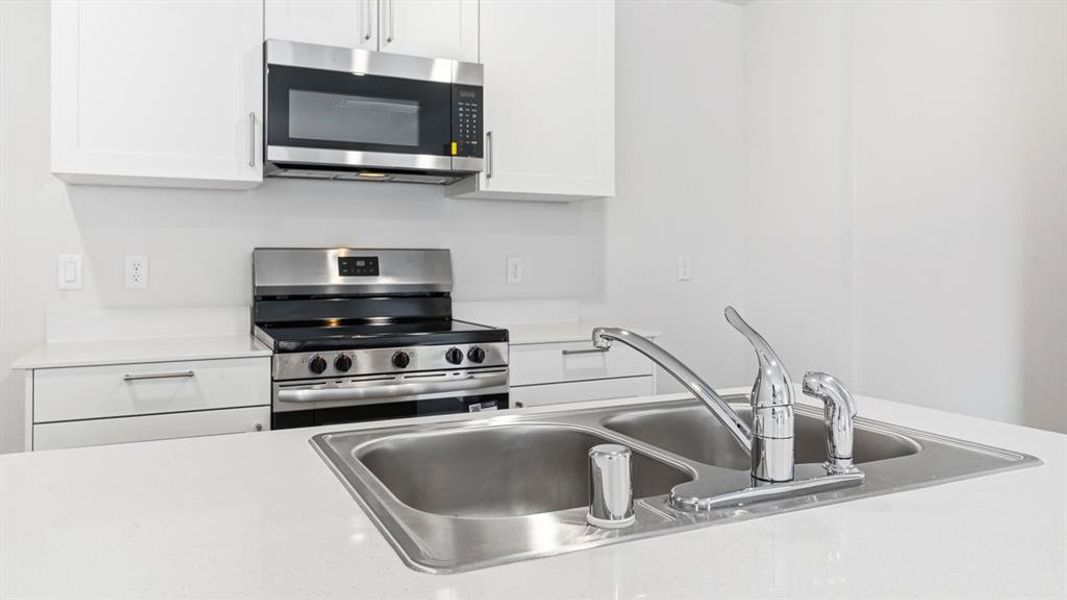 Kitchen featuring stainless steel appliances, light countertops, and white cabinetry Kitchen featuring stainless steel appliances, light countertops, and white cabinetry